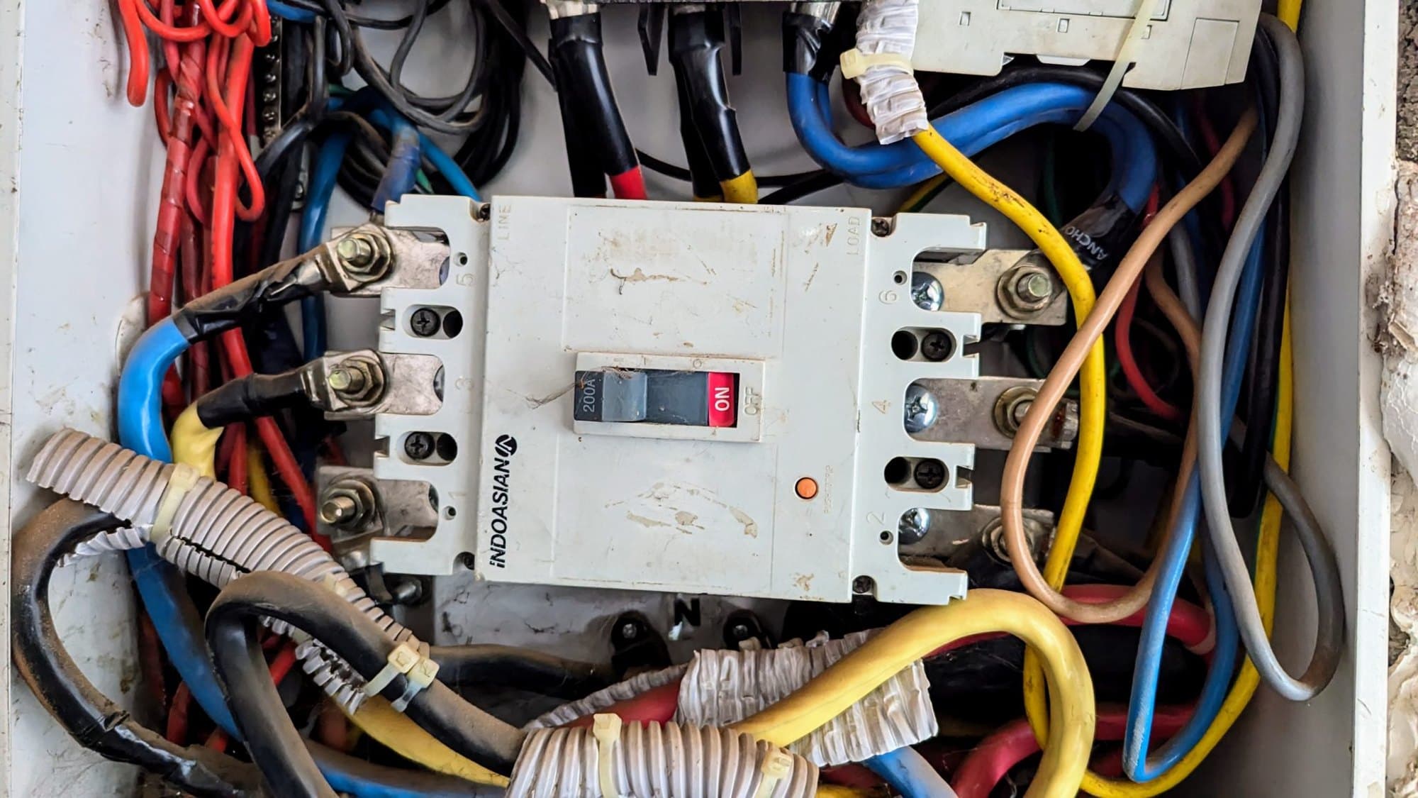 Close-up of a circuit breaker with connected cables inside an electrical panel