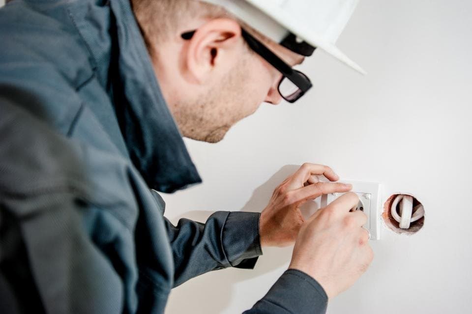 Electrician wearing a hard hat fitting a wall switch box