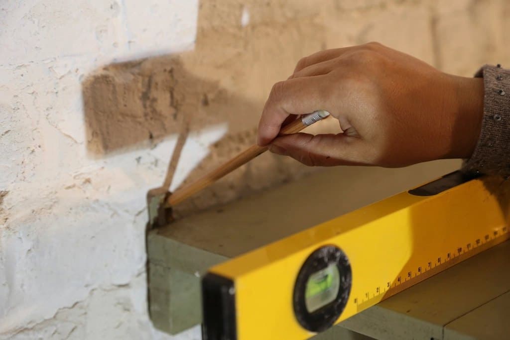 Hand marking a wall using a spirit level before a repair